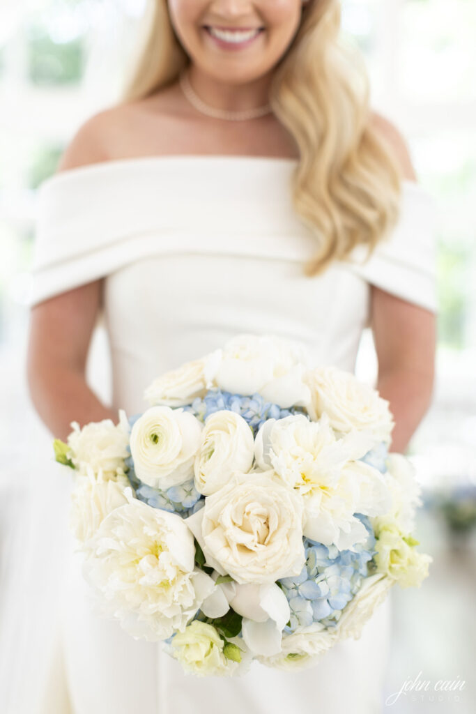 Bride holding a white rose and blue hydrangea bouquet by Sage Fine Flowers